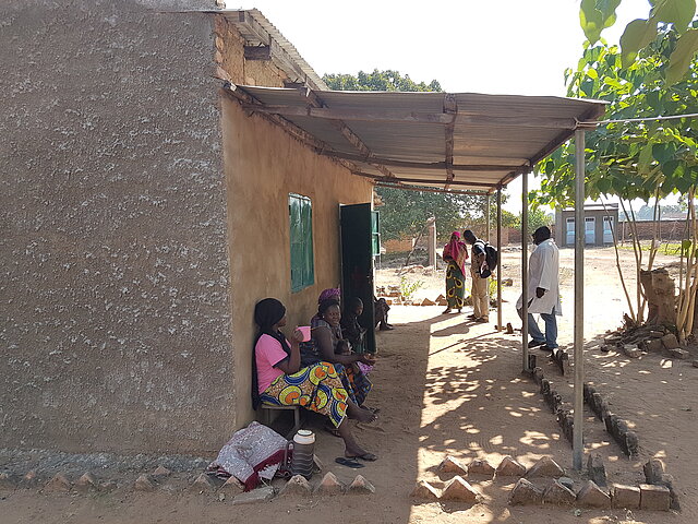 Menschen sitzen vor einer Krankenstation im Tschad