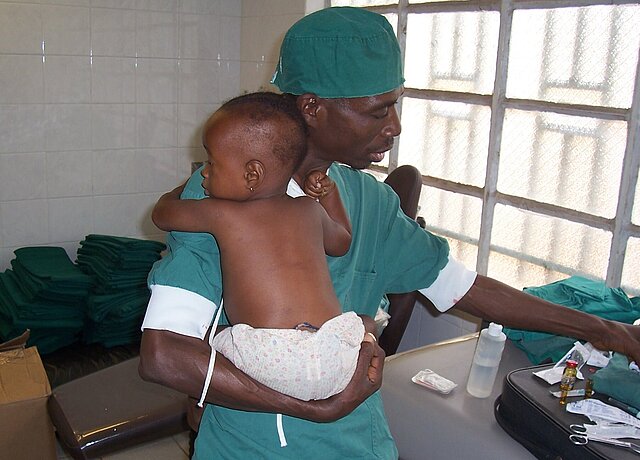 Ein kleiner Junge auf dem Arm eines Arztes in Afrika