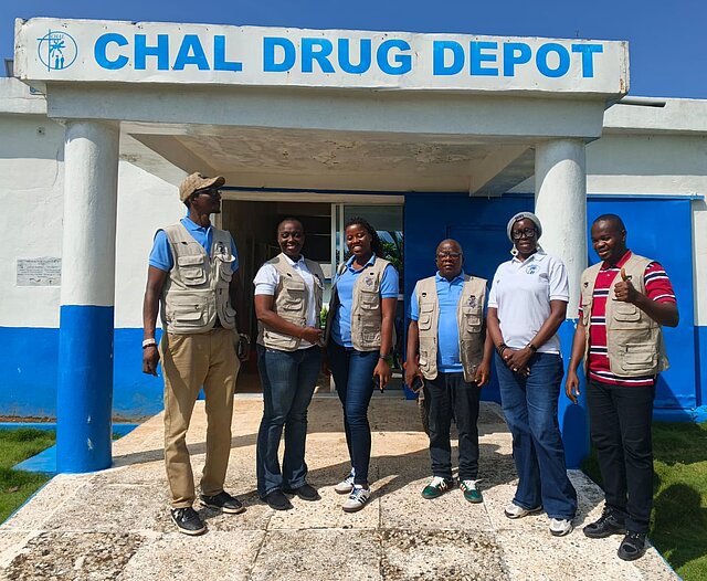 Eine Delegation aus Sierre Leone besucht ihre Kolleg:innen in Liberia. Gemeinsam stehen sie vor dem Medikamentenlager.