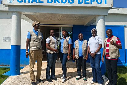Eine Delegation aus Sierre Leone besucht ihre Kolleg:innen in Liberia. Gemeinsam stehen sie vor dem Medikamentenlager.