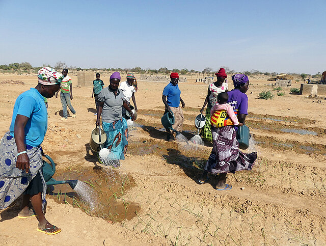 Frauen gießen auf einem trockenen Feld