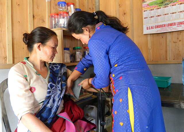 Dorfgesundheitshelferin misst den Blutdruck einer Patientin in Indien
