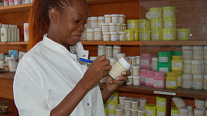 Eine Frau in Afrika vor einem Regal mit Medikamenten