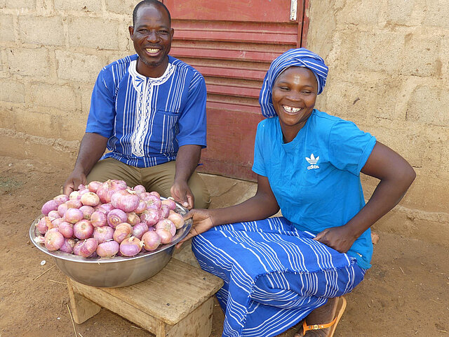 Ein Mann und eine Frau zeigen stolz die Zwiebeln, die sie selbst angebaut und geerntet haben