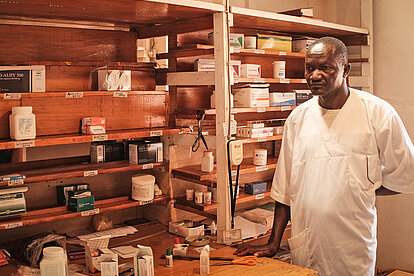 Ein Apotheker steht vor einem fast leeren Regal für Medikamente im Tschad